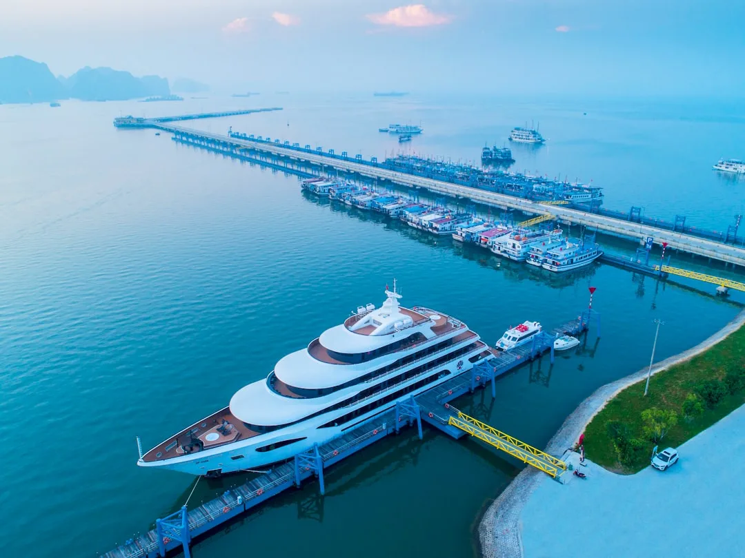 Luxury yacht docked at a long pier with boats.