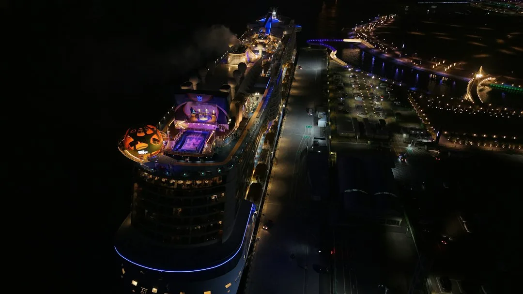 A cruise ship lit up at night beside a harbour strung with festive lights