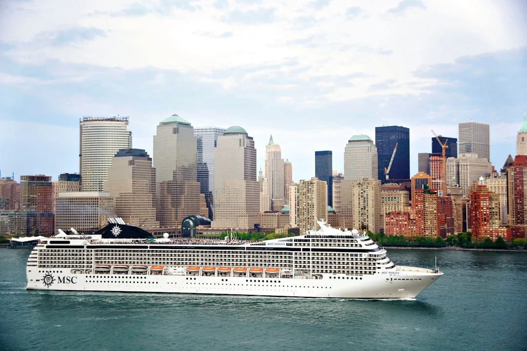 A large cruise ship sails past a city skyline.
