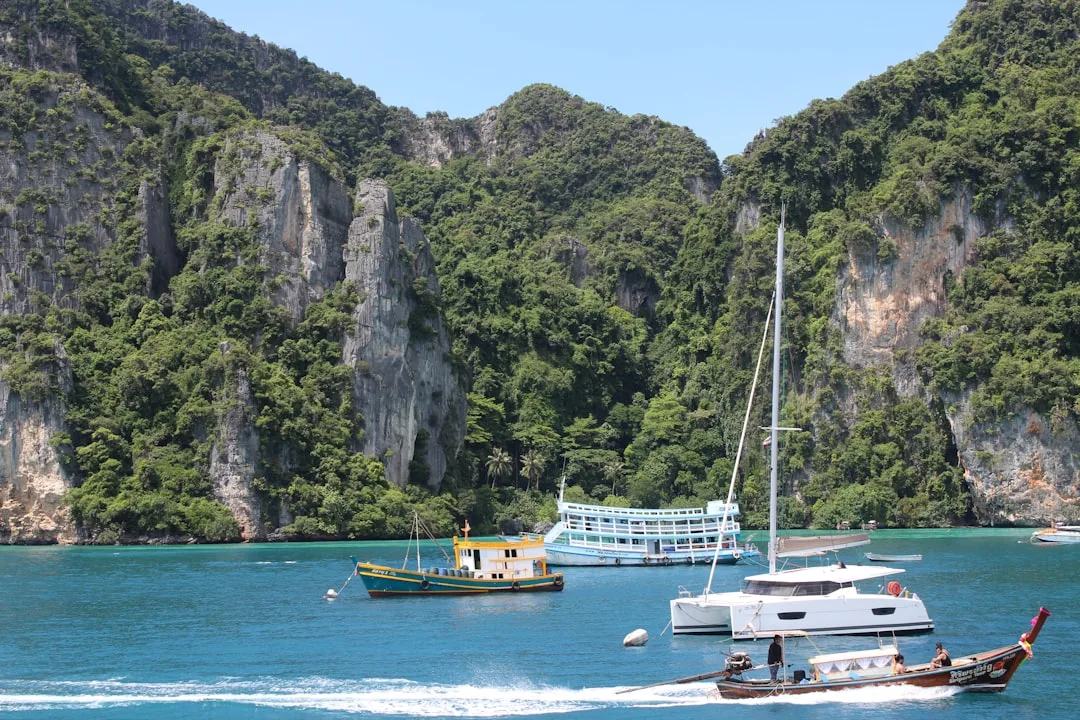 Boats sail in turquoise water near rocky, green islands.